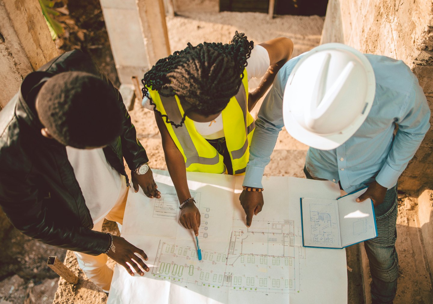 Tre professionisti dell'edilizia esaminano delle planimetrie in un cantiere.